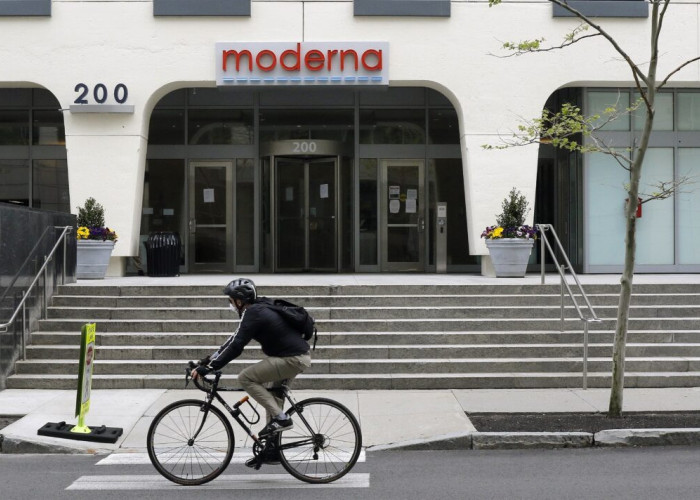 A bicyclists pedals past an entrance to a Moderna, Inc., building, Monday, May 18, 2020, in Cambridge, Mass. Moderna announced Monday that an experimental vaccine against the coronavirus showed encouraging results in very early testing, triggering hoped-f